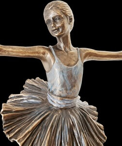 Ballerina statuette placeret på reol sammen med bøger og blomster – interiørinspiration